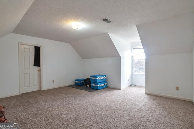 bonus room featuring vaulted ceiling, carpet floors, baseboards, and a textured ceiling