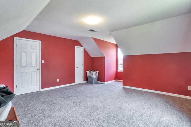 additional living space with vaulted ceiling, carpet flooring, a textured ceiling, and baseboards