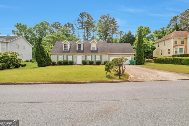 cape cod home featuring an attached garage, concrete driveway, and a front lawn