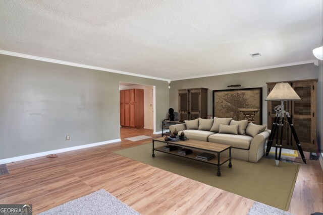 living area featuring ornamental molding, wood finished floors, baseboards, and a textured ceiling