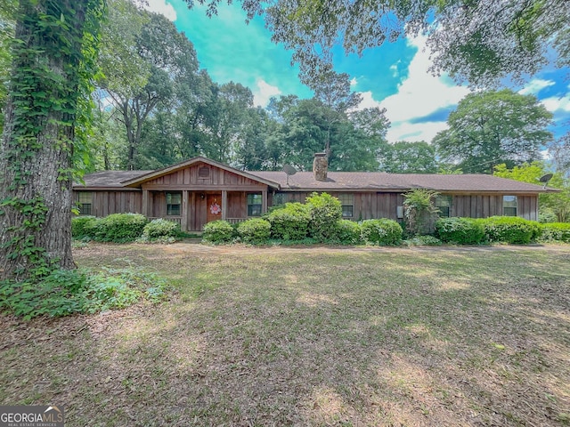 ranch-style house with a chimney and a front lawn