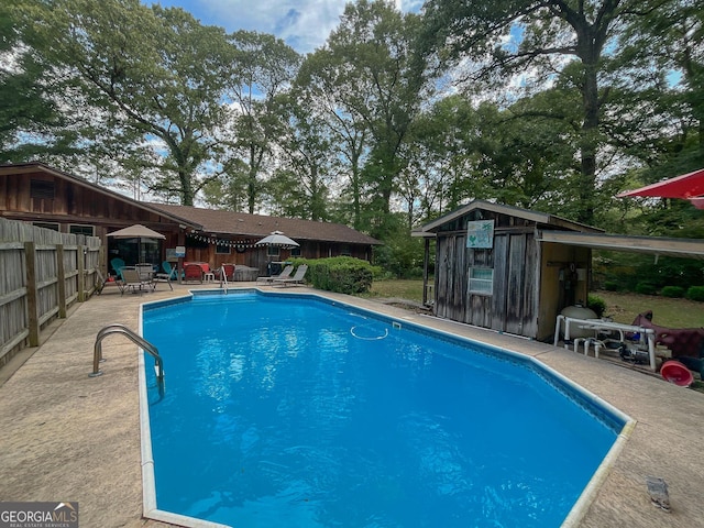 view of pool with fence, a patio area, and an outbuilding