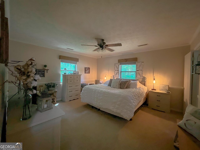 bedroom featuring light carpet, multiple windows, a ceiling fan, and ornamental molding
