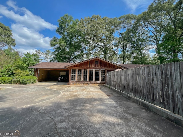 rear view of house featuring fence, driveway, an attached carport, and board and batten siding