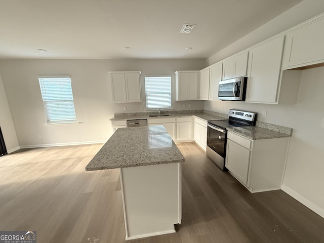 2051 Blue Sky Ave, Covington, GA 30016 - kitchen with stainless steel appliances, a sink, a kitchen island, and wood finished floors