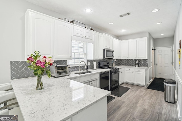 1010 Capella Creek Way, Grayson, GA 30017 - kitchen with black appliances, a sink, a peninsula, white cabinets, and recessed lighting