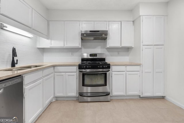 kitchen featuring stainless steel appliances, under cabinet range hood, a sink, and white cabinets