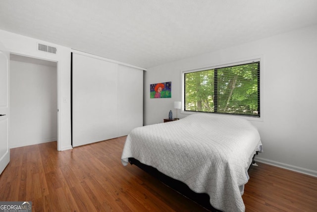 bedroom featuring wood finished floors, a closet, and baseboards