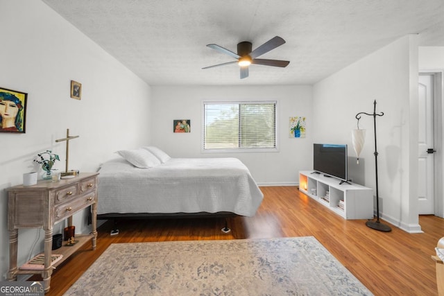 bedroom with wood finished floors, a textured ceiling, ceiling fan, and baseboards