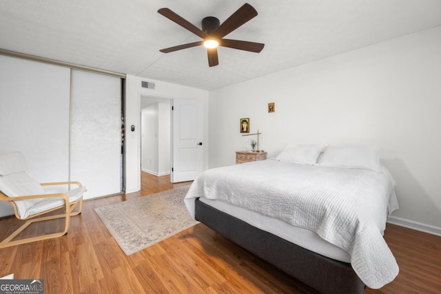 bedroom featuring wood finished floors, a closet, ceiling fan, and baseboards