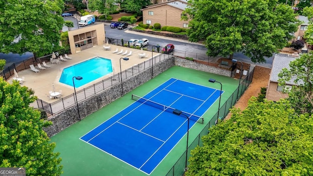view of tennis court with fence and a community pool
