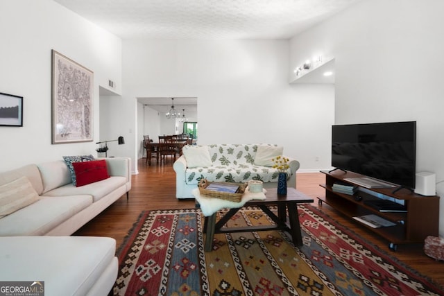 living room featuring a chandelier, wood finished floors, and a towering ceiling