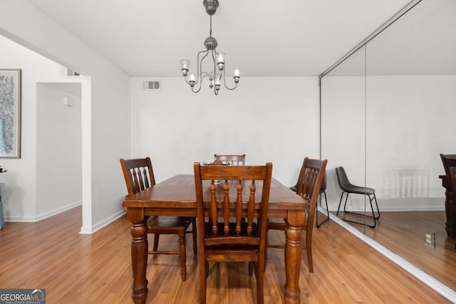 dining area featuring light wood finished floors, a chandelier, and baseboards