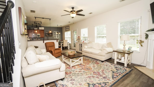 living room featuring dark wood finished floors, ceiling fan, and baseboards