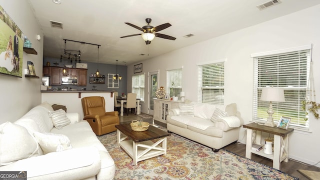 living room featuring a ceiling fan, a chandelier, and wood finished floors