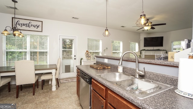 kitchen featuring stainless steel dishwasher, a sink, ceiling fan, hanging light fixtures, and brown cabinetry