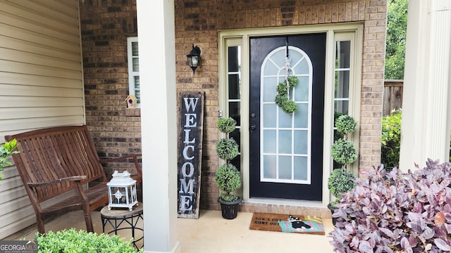 view of exterior entry featuring brick siding and a porch