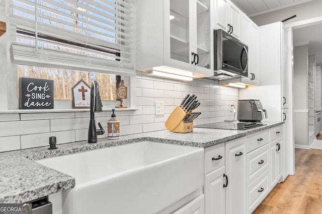 95 Farmers Academy Rd, Martin, GA 30557 - kitchen featuring stainless steel microwave, a sink, white cabinetry, glass insert cabinets, and decorative backsplash
