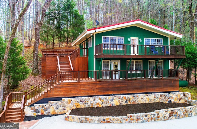 view of front facade featuring stairway, a deck, and a view of trees