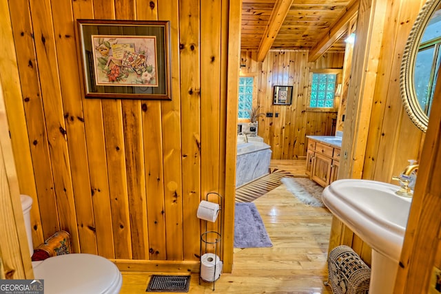 full bathroom with wooden ceiling, wood walls, hardwood / wood-style floors, beam ceiling, and toilet