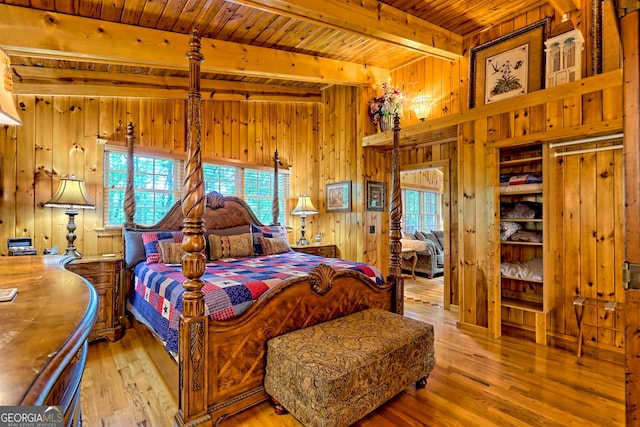 bedroom featuring wood ceiling, beam ceiling, wooden walls, multiple windows, and hardwood / wood-style floors
