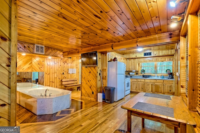 bathroom featuring wood walls, a sink, wood finished floors, a garden tub, and wooden ceiling