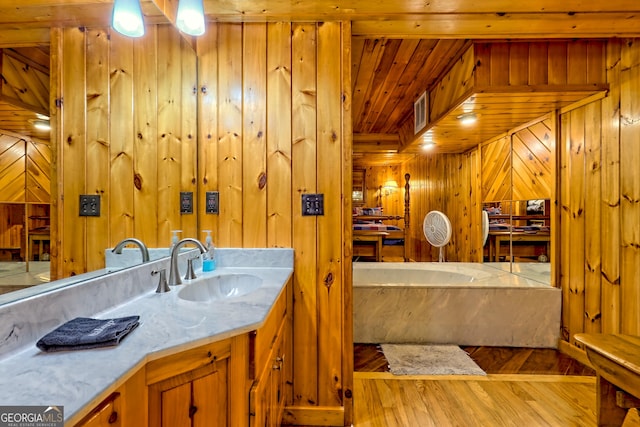 bathroom featuring wood walls, wood finished floors, a bath, wooden ceiling, and vanity