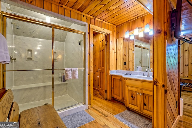 bathroom with wooden walls, wood ceiling, a shower stall, wood finished floors, and vanity