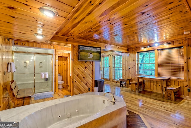 full bathroom featuring toilet, wooden walls, a stall shower, hardwood / wood-style flooring, and a jetted tub