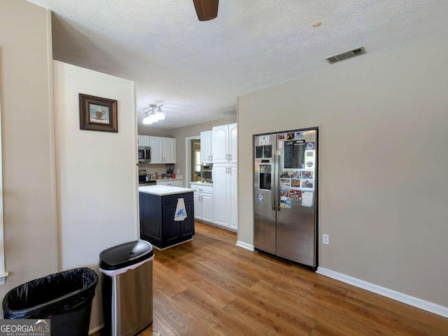 2003 Brenda Ln, Vidalia, GA 30474 - kitchen featuring appliances with stainless steel finishes, white cabinets, wood finished floors, light countertops, and baseboards