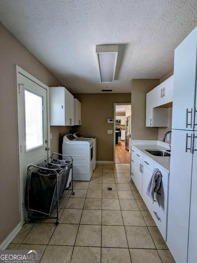2003 Brenda Ln, Vidalia, GA 30474 - kitchen featuring a sink, separate washer and dryer, light countertops, white cabinets, and light tile patterned floors