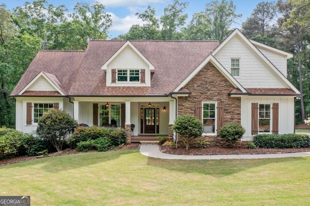 view of front facade featuring a front yard, stone siding, board and batten siding, and covered porch