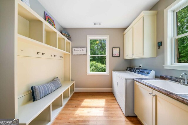 laundry room featuring separate washer and dryer, cabinet space, plenty of natural light, and light wood finished floors
