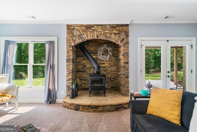 living area with a wood stove, french doors, carpet floors, baseboards, and ornamental molding