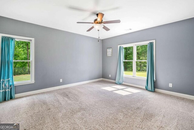 unfurnished room with plenty of natural light, a ceiling fan, carpet flooring, and baseboards