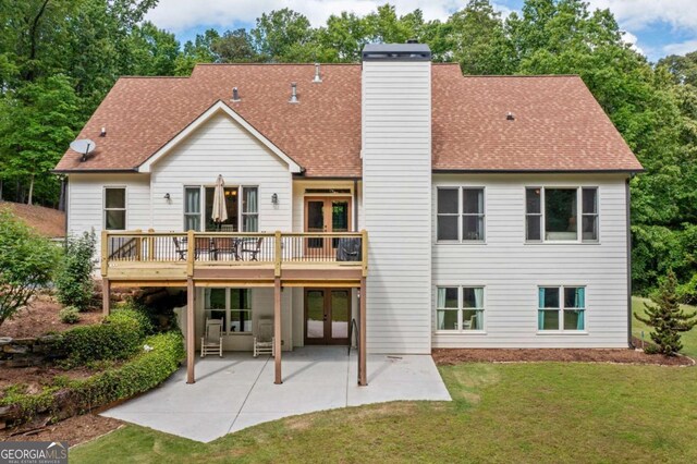 rear view of property with french doors, a lawn, a chimney, a patio area, and a shingled roof