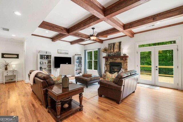 living area featuring a ceiling fan, light wood finished floors, coffered ceiling, beam ceiling, and a fireplace