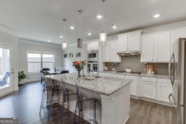 kitchen with appliances with stainless steel finishes, crown molding, wood finished floors, under cabinet range hood, and white cabinets