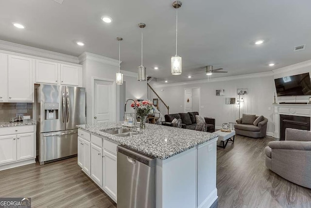 kitchen featuring stainless steel appliances, a sink, open floor plan, crown molding, and ceiling fan