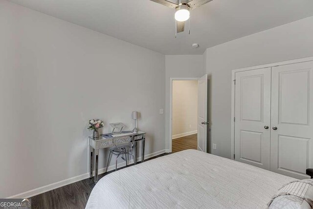 bedroom with dark wood-type flooring, baseboards, a closet, and a ceiling fan