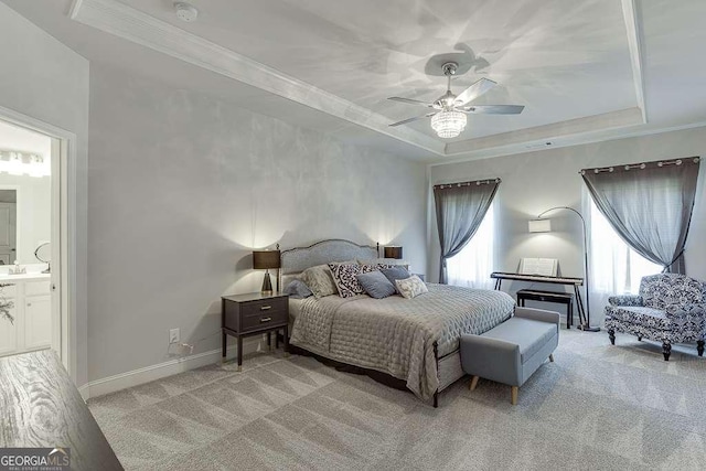 bedroom featuring a tray ceiling, light colored carpet, ornamental molding, baseboards, and ceiling fan