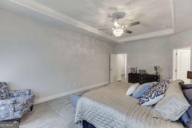 carpeted bedroom with a raised ceiling, baseboards, ceiling fan, and ornamental molding