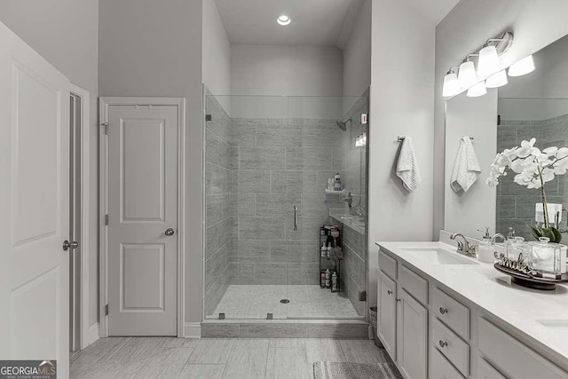 bathroom with a shower stall, double vanity, and recessed lighting