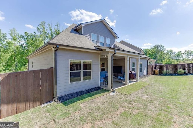 rear view of property with a patio and roof with shingles