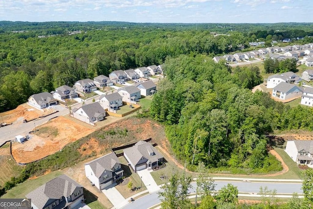 aerial view of property's location featuring nearby suburban area and a heavily wooded area