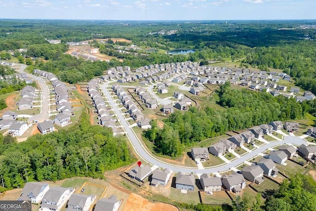 view of property location with nearby suburban area and a heavily wooded area