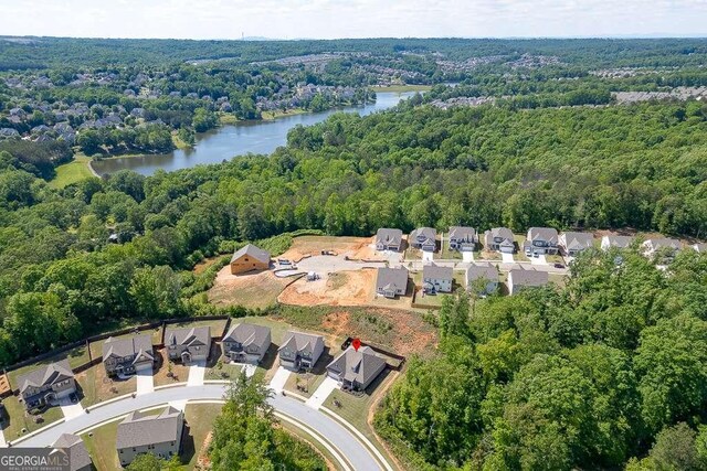 aerial perspective of suburban area with a heavily wooded area and a nearby body of water