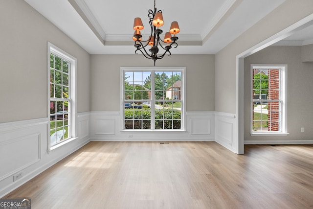 1429 Kentmire Ct, Locust Grove, GA 30248 - unfurnished dining area featuring a chandelier, a raised ceiling, ornamental molding, a wainscoted wall, and light wood-style floors