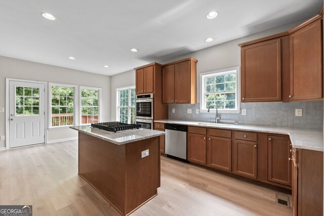 1429 Kentmire Ct, Locust Grove, GA 30248 - kitchen featuring appliances with stainless steel finishes, a sink, light wood-type flooring, a kitchen island, and healthy amount of natural light