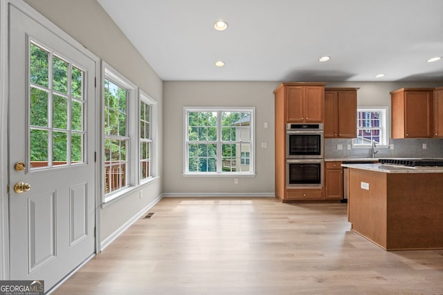 1429 Kentmire Ct, Locust Grove, GA 30248 - kitchen with brown cabinetry, double oven, light wood finished floors, tasteful backsplash, and recessed lighting